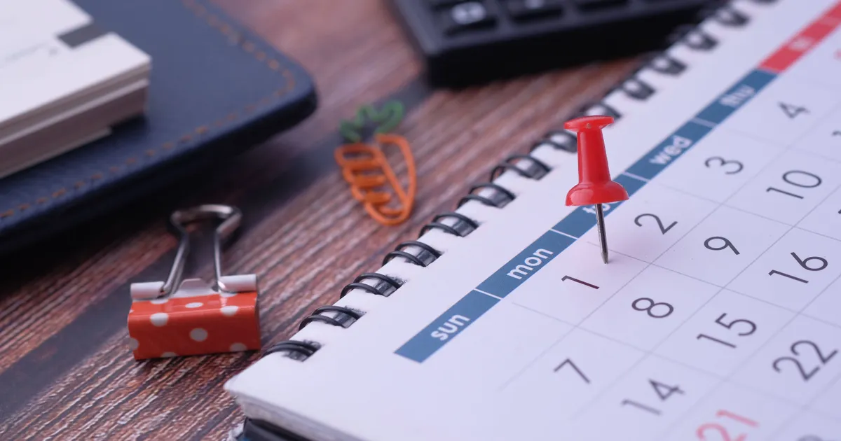 Bureaukalender met een rode punaise op een datum